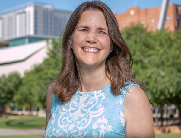 Elizabeth Lightfoot headshot - fair-skinned woman, smiling, brown hair, blue and white shirt