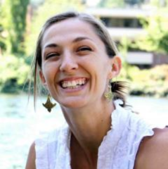 Heather Voelkel headshot - fair-skinned woman, smiling, brown hair, white shirt, earrings