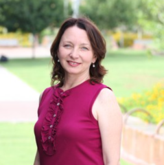 Judy Krysik headshot - fair-skinned woman, smiling, brown hair, magenta shirt, earrings 