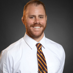 Marcos Martinez headshot - fair-skinned man, smiling, red hair and beard, white collared shirt, orange-and-black-striped tie